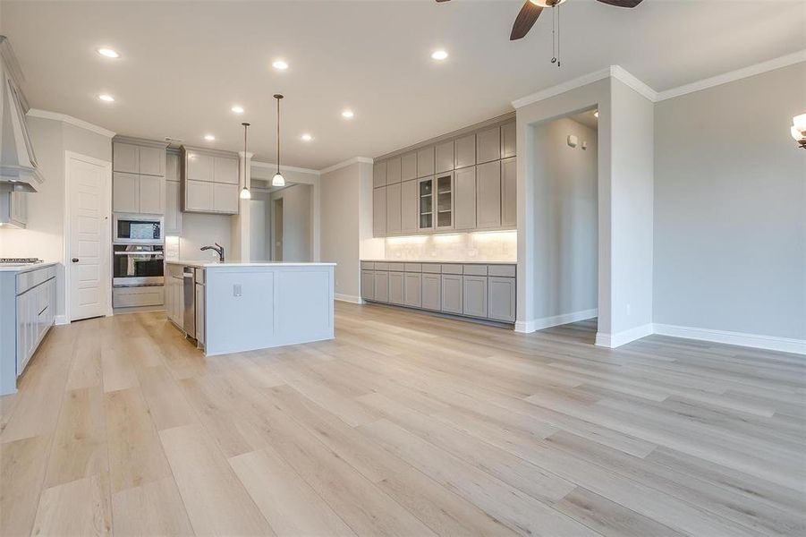 Kitchen featuring a kitchen island with sink, appliances with stainless steel finishes, light wood-type flooring, and ceiling fan