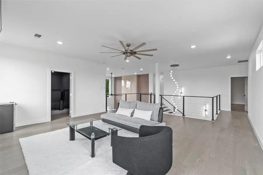 Open-concept upper-level living area with light wood-finish flooring and recessed lighting