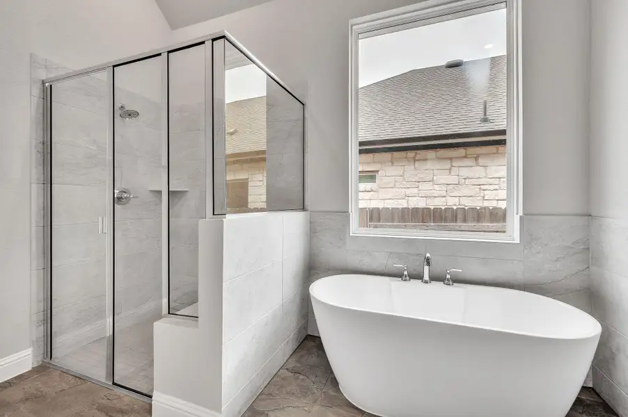 Full bathroom featuring a stall shower, a freestanding bath, and tile walls Full bathroom featuring a stall shower, a freestanding bath, and tile walls
