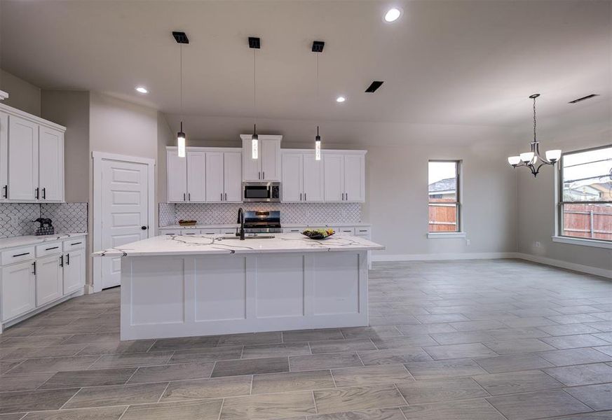 Kitchen featuring appliances with stainless steel finishes, a kitchen island with sink, and white cabinets