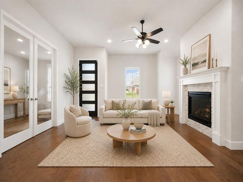 Spacious living area featuring hardwood flooring, a contemporary fireplace with a white mantel and stone surround, and recessed lighting