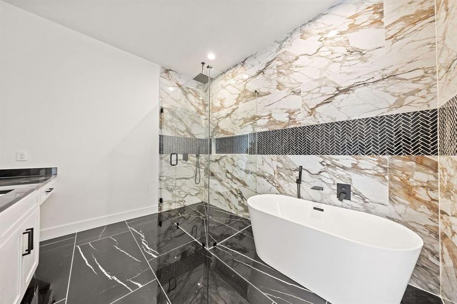 Full bathroom featuring marble tiled flooring, a freestanding tub, a marble finish shower, vanity, and baseboards Full bathroom featuring marble tiled flooring, a freestanding tub, a marble finish shower, vanity, and baseboards