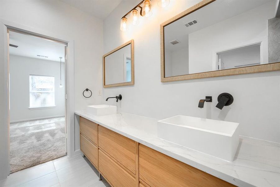 Bathroom with light colored carpet, double vanity, and light tile patterned floors