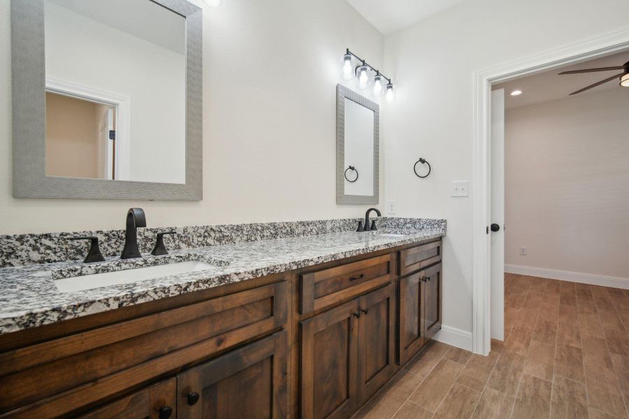 Bathroom with double vanity, a sink, baseboards, and wood finished floors Bathroom with double vanity, a sink, baseboards, and wood finished floors
