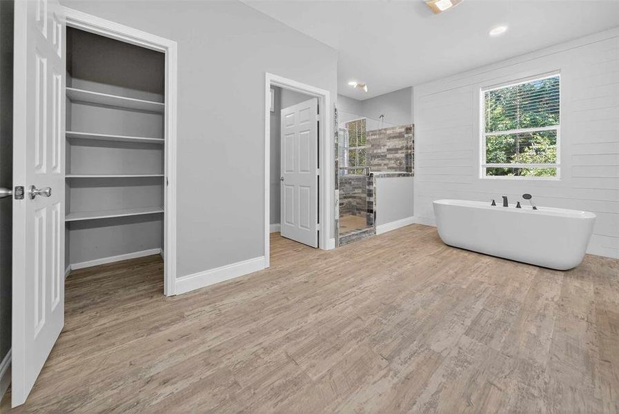 Full bathroom with a stall shower, a soaking tub, light wood-type flooring, and a walk in closet