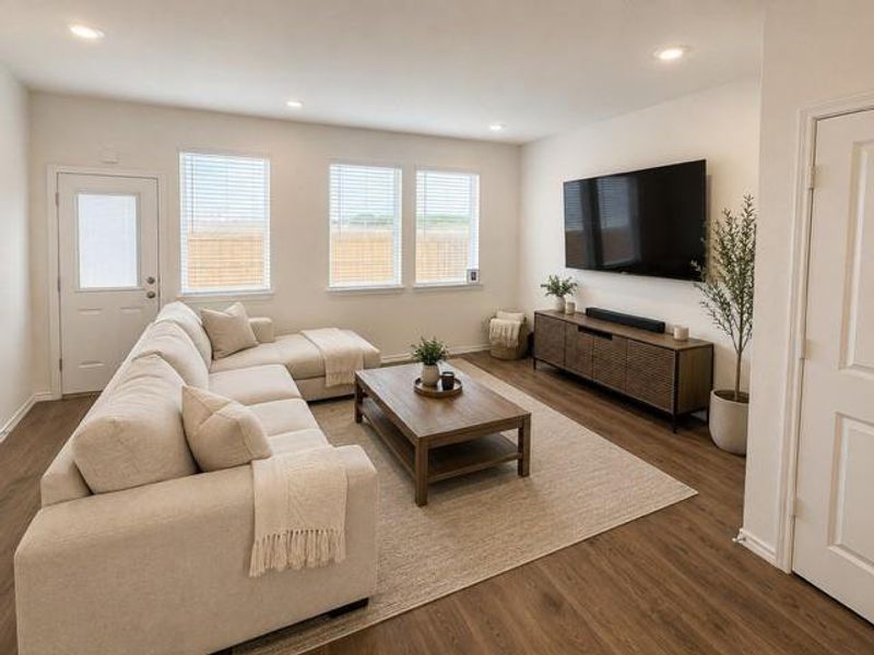 Living area featuring wood-finish flooring, recessed lighting, and three large windows with blinds Living area featuring wood-finish flooring, recessed lighting, and three large windows with blinds