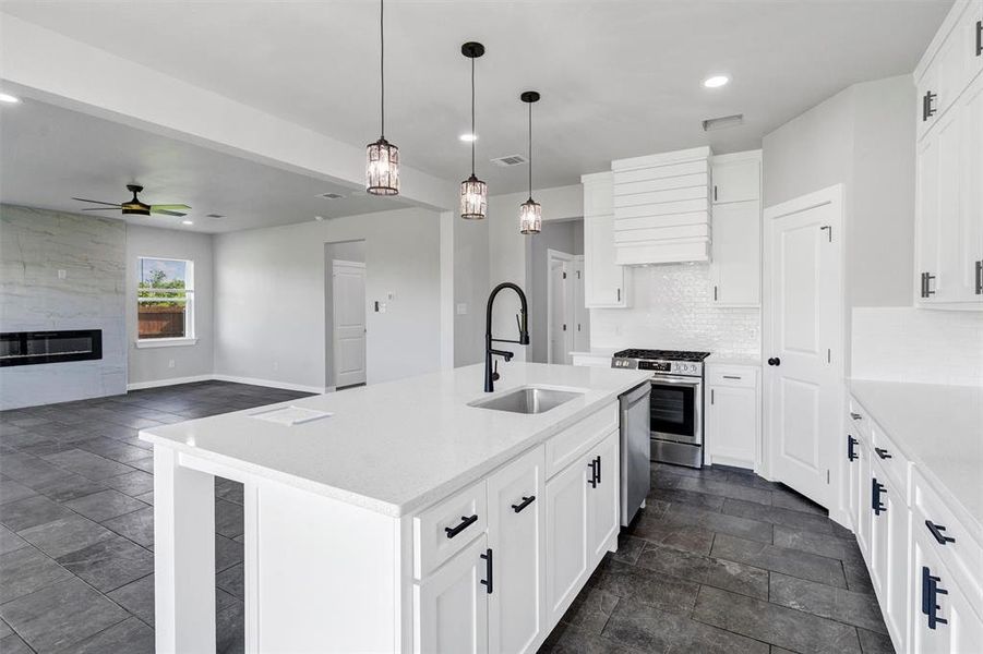 Kitchen featuring a sink, appliances with stainless steel finishes, recessed lighting, dark stone finish floors, and a ceiling fan