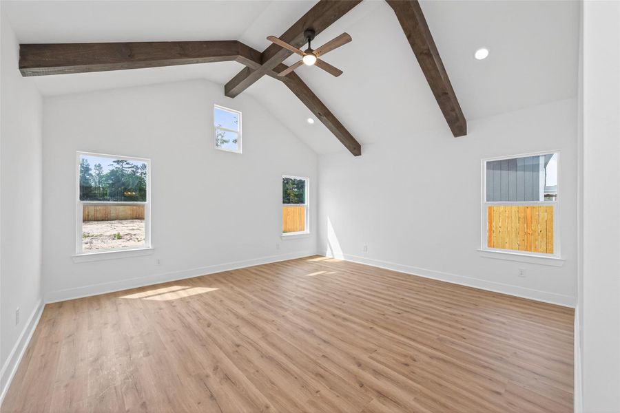 Oversized primary suite featuring vaulted ceilings with wood beam accents and plenty of natural light.