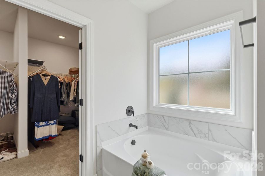 Relaxing soaking tub with elegant tile surround and natural light for a spa-like feel.