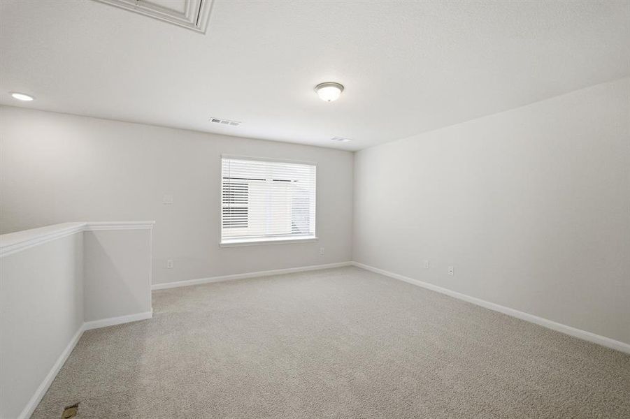 Bright room featuring light grey carpeting, recessed lighting, and a single window with blinds