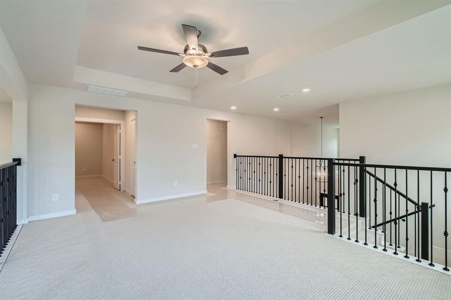 Empty room with a ceiling fan, light carpet, a raised ceiling, and recessed lighting Empty room with a ceiling fan, light carpet, a raised ceiling, and recessed lighting