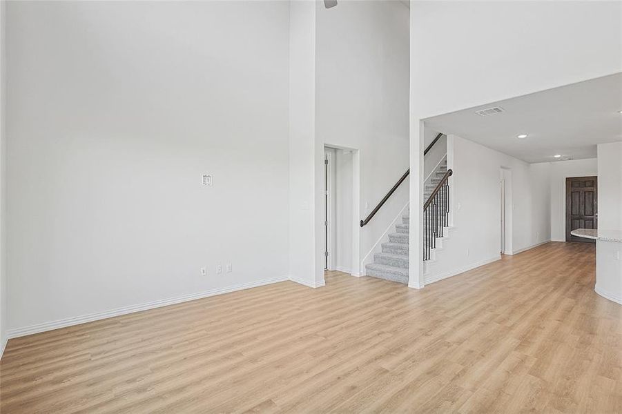 Unfurnished living room with a towering ceiling and light wood-type flooring