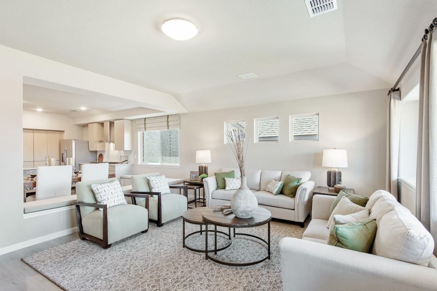 Open-concept living room with neutral sofas, accent chairs, and round coffee table, open to kitchen beyond Open-concept living room with neutral sofas, accent chairs, and round coffee table, open to kitchen beyond