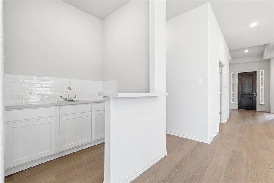 Bar with white cabinets, recessed lighting, and light wood finished floors Bar with white cabinets, recessed lighting, and light wood finished floors