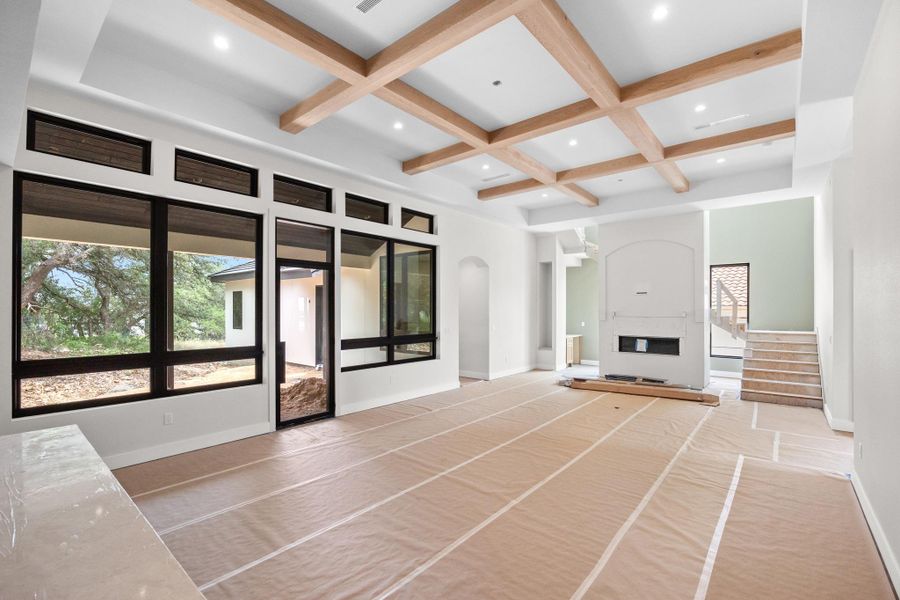 Spacious living area featuring a coffered ceiling with wood beams, recessed lighting, a built-in fireplace, and large black-framed windows