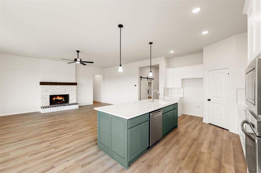 Kitchen featuring dual tone cabinetry, a fireplace, light wood finished floors, open floor plan, and a ceiling fan