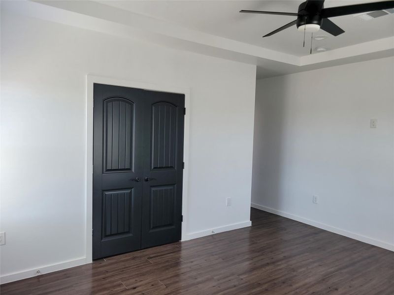 Rich hardwood-style flooring extends across this tranquil bedroom, featuring a tray ceiling and a discreet closet. Rich hardwood-style flooring extends across this tranquil bedroom, featuring a tray ceiling and a discreet closet.