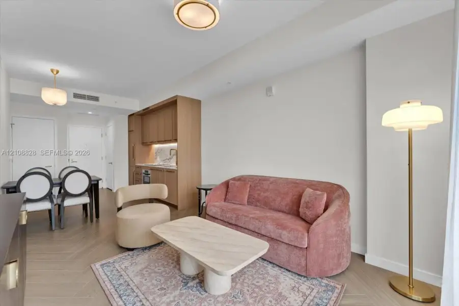 Open-concept living space featuring wood-finish herringbone flooring, custom light wood cabinetry, stone backsplash, and recessed ceiling lighting