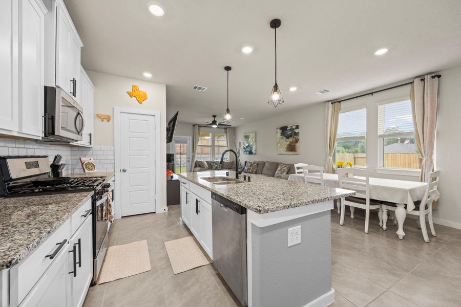 This view captures the inviting, open layout, perfect for entertaining. The kitchen's large island overlooks a cozy dining area and a spacious living room, keeping everyone connected.