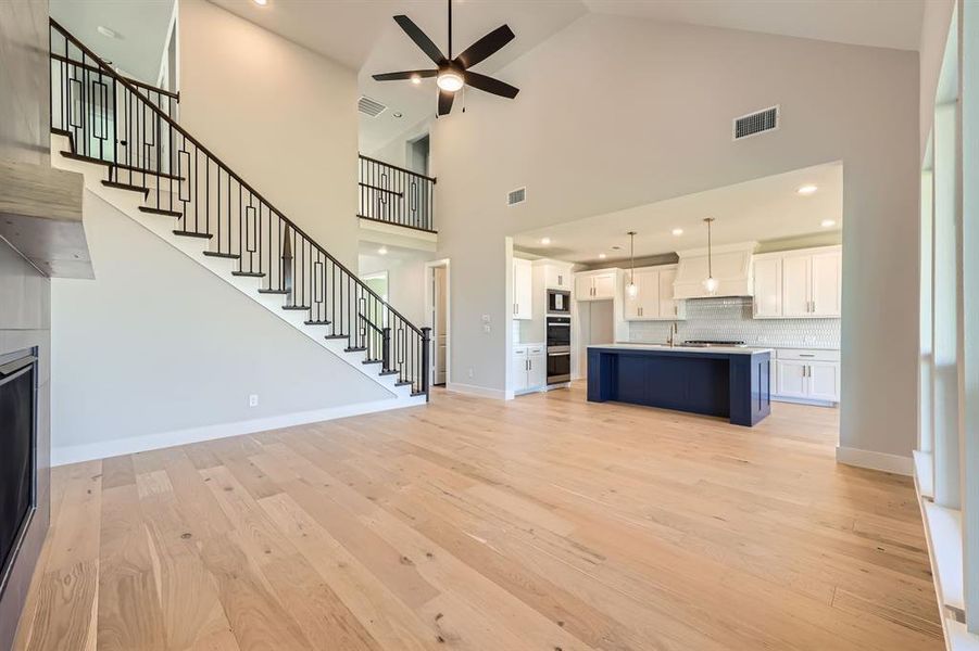 Unfurnished living room with light hardwood / wood-style flooring, high vaulted ceiling, and ceiling fan