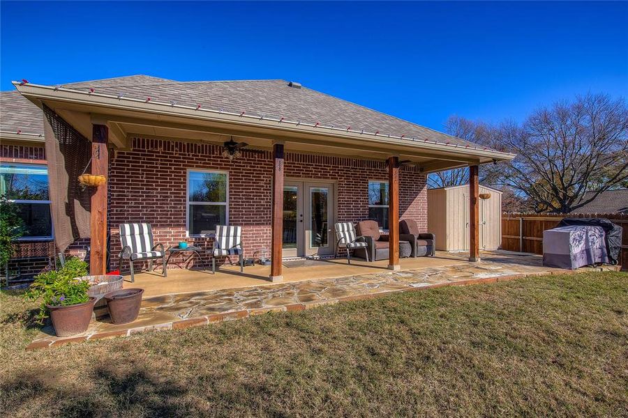 Rear view of property featuring a storage shed, a yard, and a patio