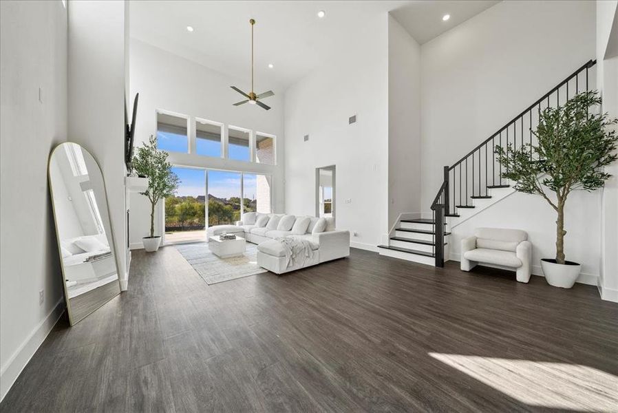 Living room featuring dark wood-style floors, recessed lighting, stairs, and baseboards