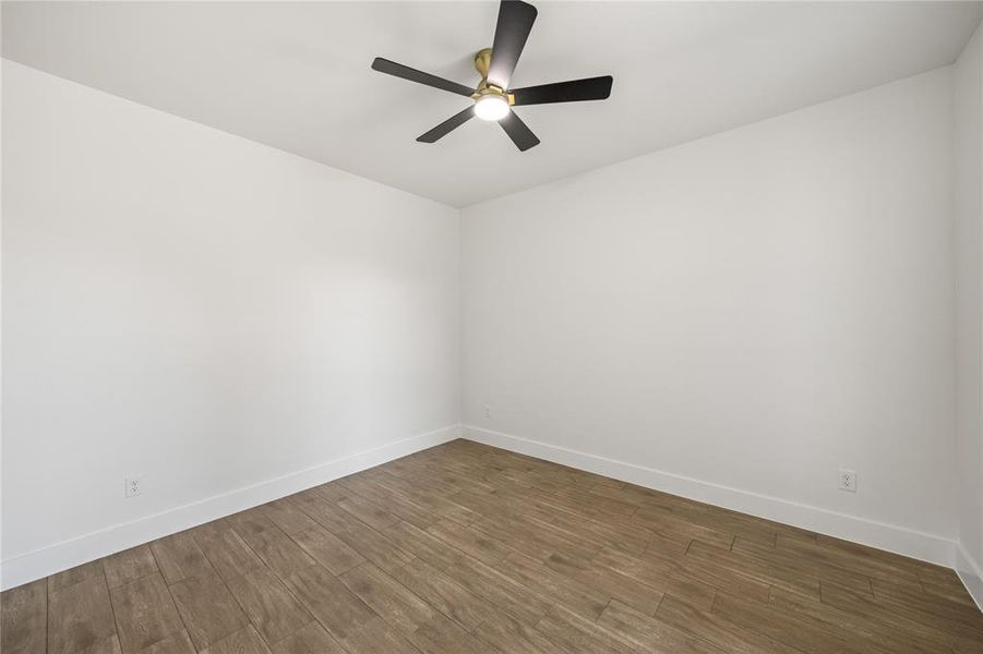 Spare room with dark wood-type flooring and ceiling fan