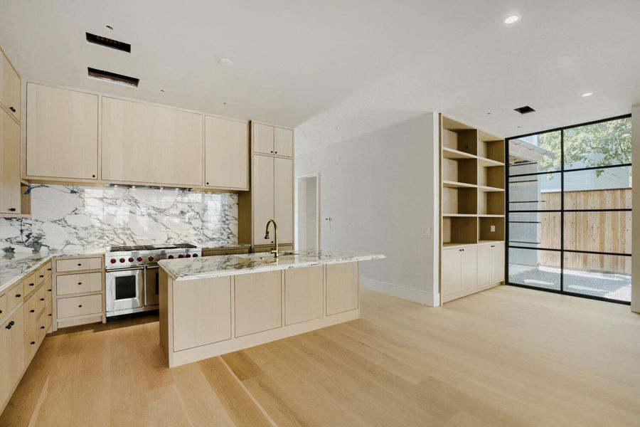 A well-lit kitchen with sleek wooden cabinetry and a marble backsplash.