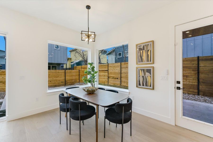 The corner dining nook is wrapped in windows that offer views of the private, fenced-in yard. Whether its a casual brunch or an intimate dinner, the designer lighting and light oak flooring provide an elegant, organic atmosphere.