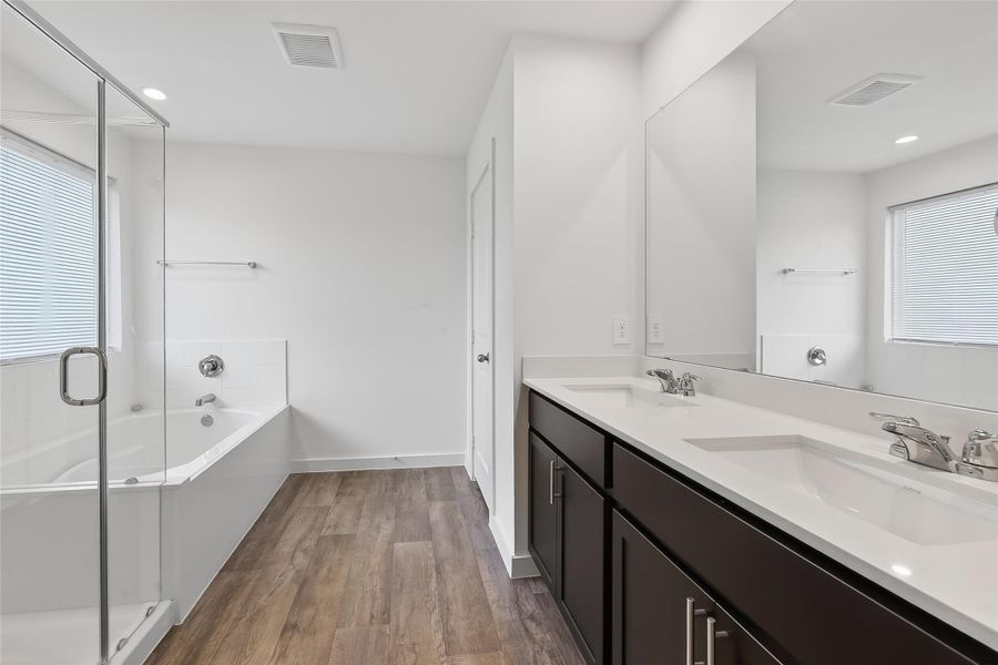 Elegant primary bathroom with a glass-enclosed shower, deep soaking tub, and dual sinks