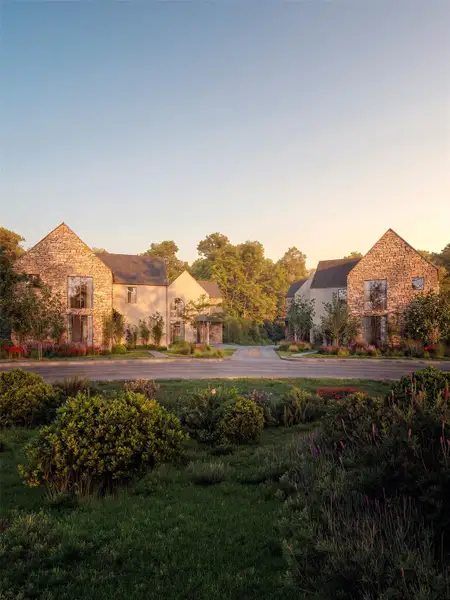 Stone and stucco homes with manicured landscaping line a quiet street at sunset. Stone and stucco homes with manicured landscaping line a quiet street at sunset.