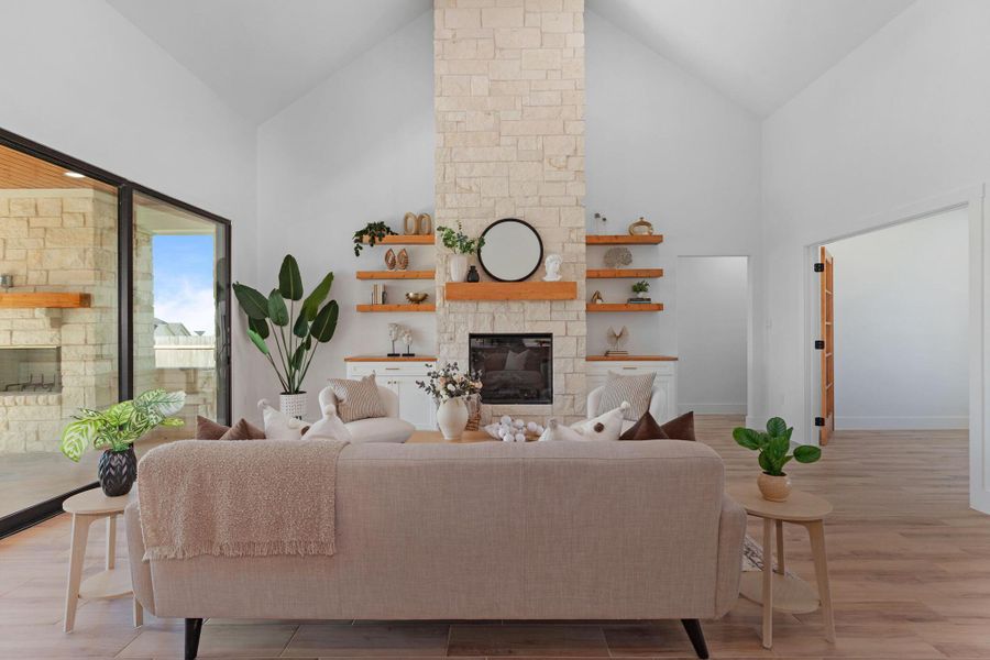 Living room featuring a stone fireplace, light wood-type flooring, and vaulted ceiling Living room featuring a stone fireplace, light wood-type flooring, and vaulted ceiling
