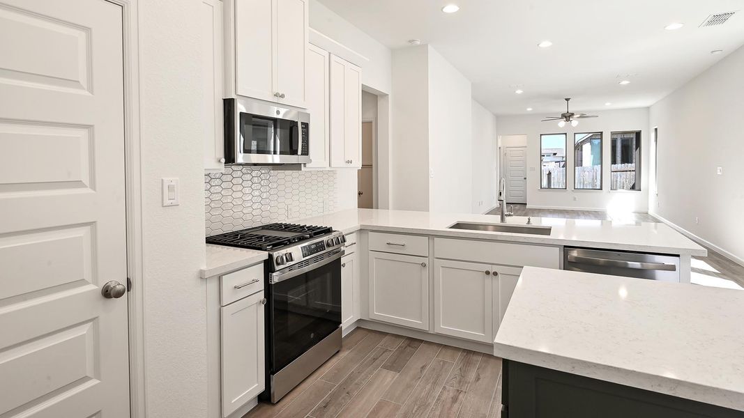 Kitchen featuring stainless steel appliances, a peninsula, light wood-style flooring, recessed lighting, and tasteful backsplash Kitchen featuring stainless steel appliances, a peninsula, light wood-style flooring, recessed lighting, and tasteful backsplash