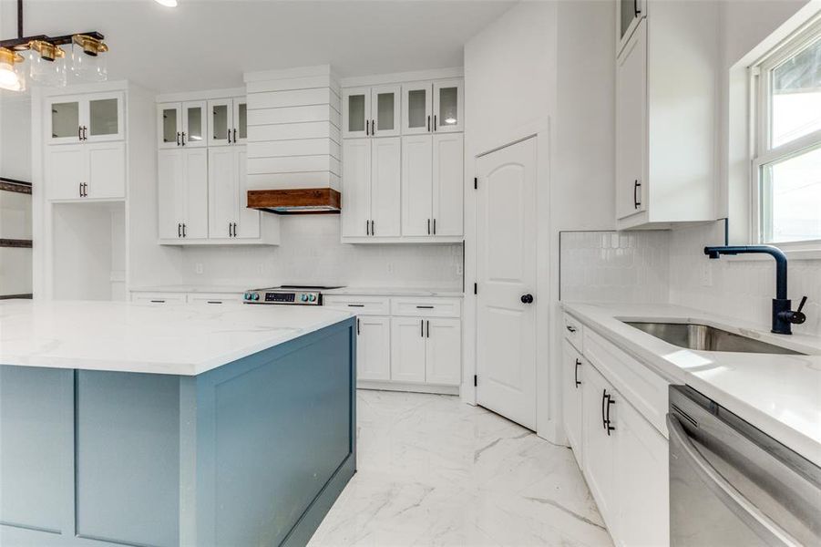 Kitchen featuring sink, white cabinets, custom exhaust hood, and appliances with stainless steel finishes