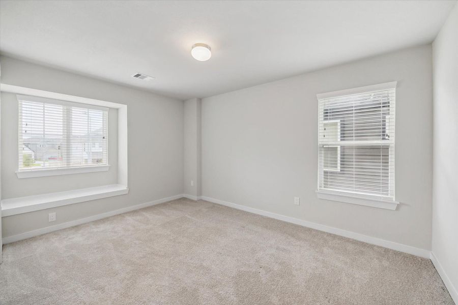 This bright, spacious room features neutral carpeting, a large window with a built-in bench, and ample natural light, perfect for a cozy bedroom. This bright, spacious room features neutral carpeting, a large window with a built-in bench, and ample natural light, perfect for a cozy bedroom.
