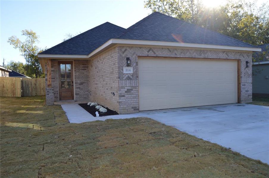 Single story home with a garage and a front lawn