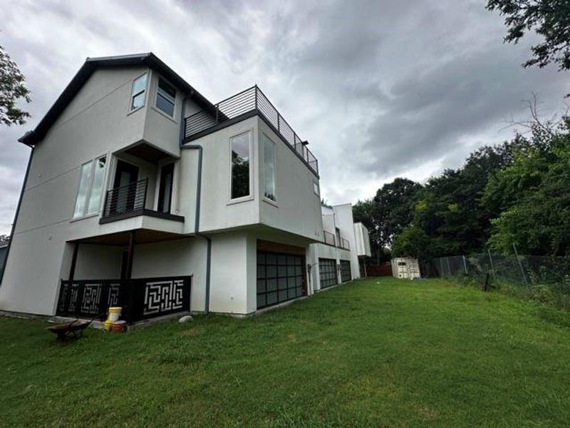 Rear view of house featuring an attached garage, stucco siding, and a balcony
