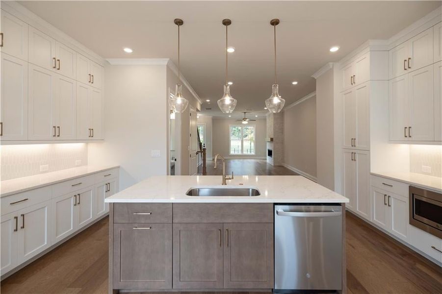 Kitchen featuring white cabinetry, stainless steel appliances, sink, and a center island with sink