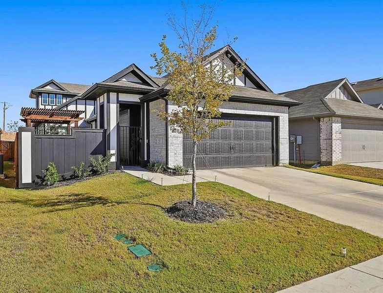 View of front of property with a pergola, a front yard, and a garage