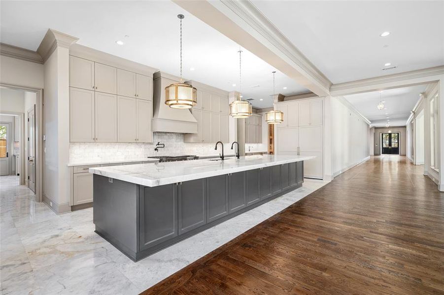 The magazine-worthy kitchen wows with a massive island topped by designer pendants. Custom two-tone cabinetry trimmed with quartz and quartzite adds to the impeccable ambiance.