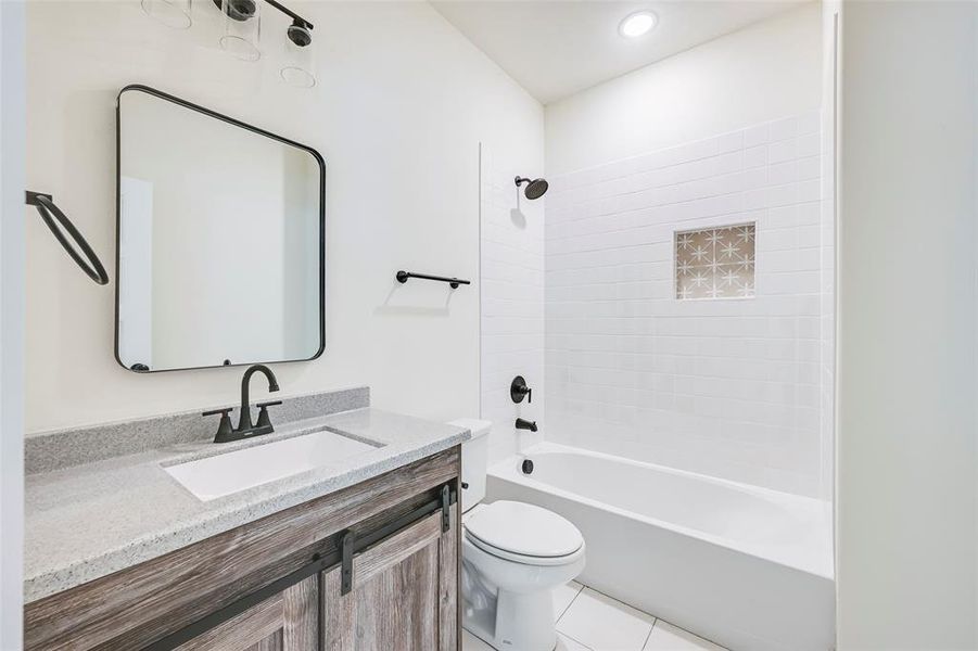 Bathroom featuring a white subway tile tub surround with recessed niche, a white tub, and a white toilet Bathroom featuring a white subway tile tub surround with recessed niche, a white tub, and a white toilet