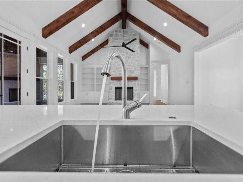 Kitchen featuring a fireplace, light stone counters, recessed lighting, a ceiling fan, and built in features