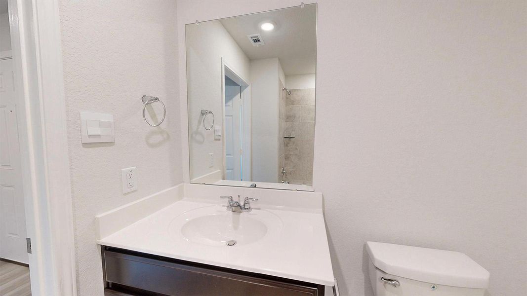 Bathroom vanity featuring an integrated sink, polished chrome faucet, and expansive wall-mounted mirror
