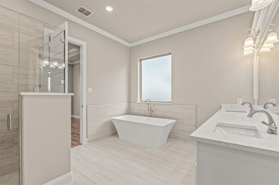 Full bath with a shower stall, double vanity, crown molding, tile walls, and a freestanding bath Full bath with a shower stall, double vanity, crown molding, tile walls, and a freestanding bath