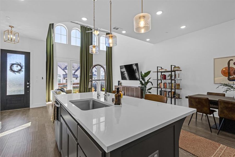 Kitchen with recessed lighting, pendant lighting, dark wood finished floors, light stone countertops, and a center island with sink