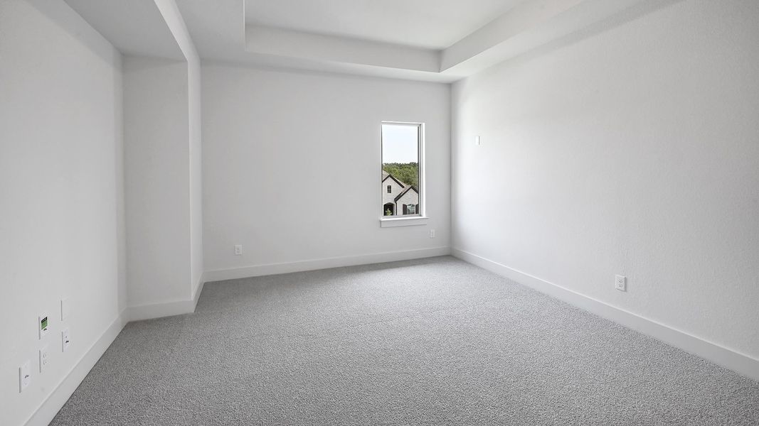 Carpeted spare room featuring baseboards and a raised ceiling
