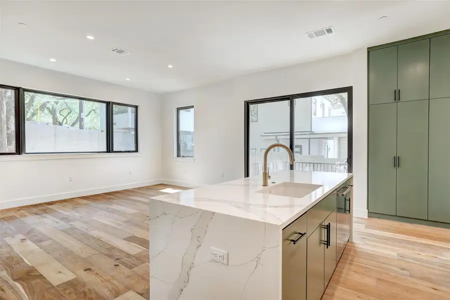 Kitchen featuring green cabinets, a sink, light wood finished floors, an island with sink, and recessed lighting