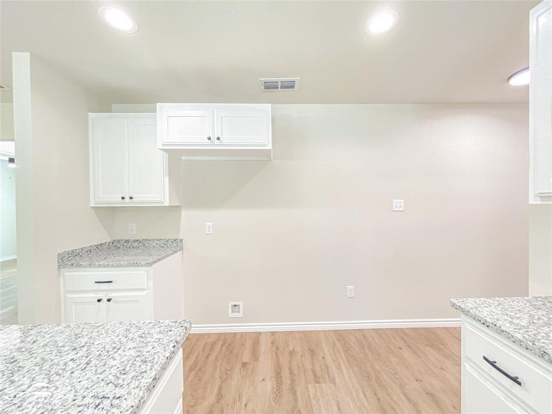 Kitchen with white cabinets, light wood finished floors, light stone counters, and recessed lighting Kitchen with white cabinets, light wood finished floors, light stone counters, and recessed lighting