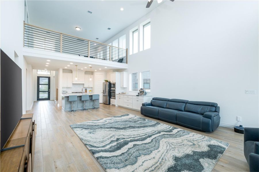 Living room/Dining area featuring recessed lighting, light wood-style floors, a high ceiling, and ceiling fan