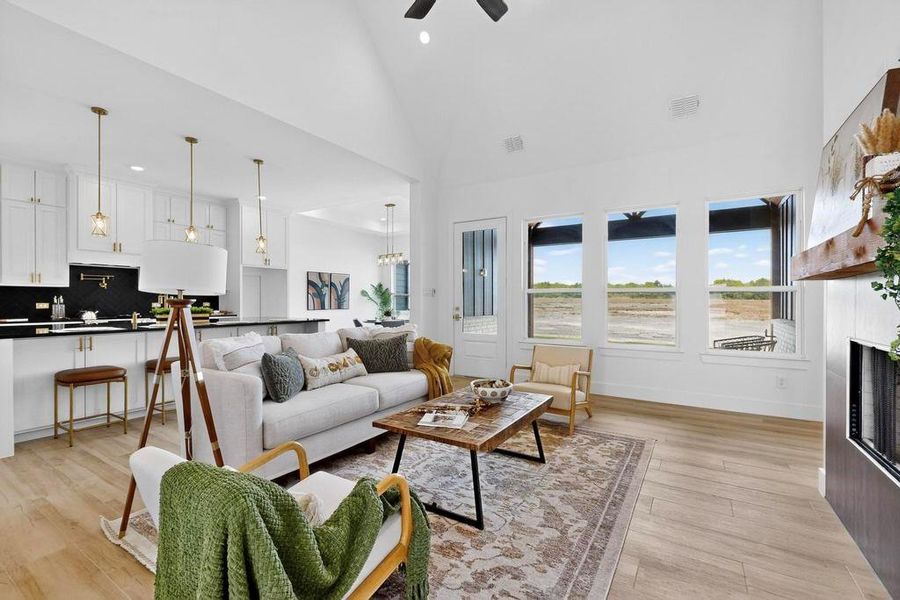 Living room with high vaulted ceiling, light wood-style floors, a fireplace, recessed lighting, and a ceiling fan